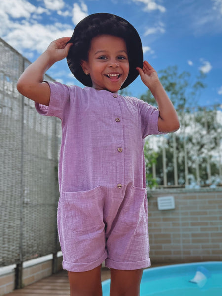 Menina com macacão curto lavanda e chapéu bucket - Loja com macacão jardineira macaquinho unissex  para infantil online
